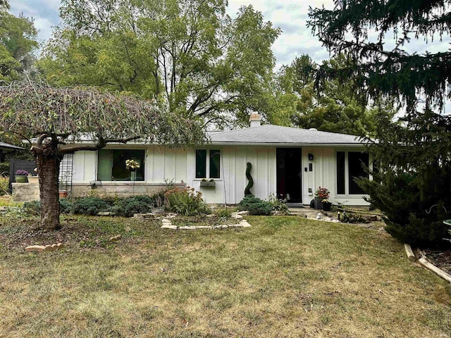 ranch-style house with a front lawn, board and batten siding, and a chimney