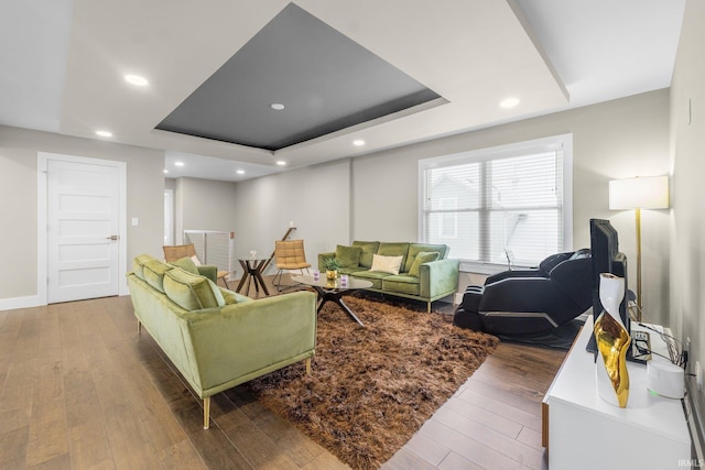 living room featuring baseboards, a tray ceiling, hardwood / wood-style flooring, and recessed lighting