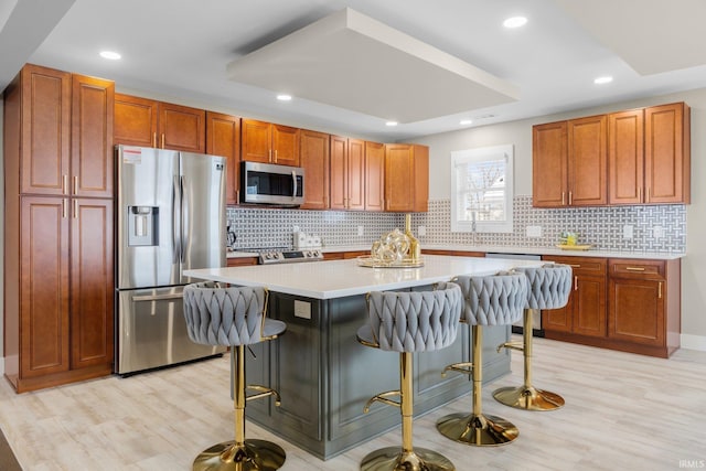 kitchen featuring appliances with stainless steel finishes, a center island, light wood-type flooring, and a breakfast bar area