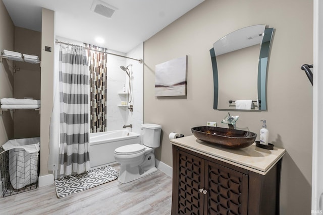 bathroom featuring toilet, wood finished floors, visible vents, vanity, and shower / bath combination with curtain