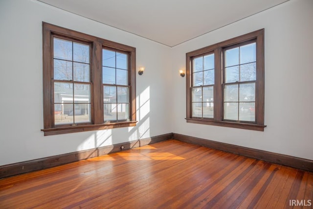 empty room with hardwood / wood-style floors and baseboards