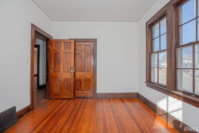 unfurnished room featuring baseboards, visible vents, and hardwood / wood-style floors