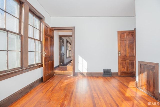 empty room with visible vents, baseboards, and hardwood / wood-style flooring