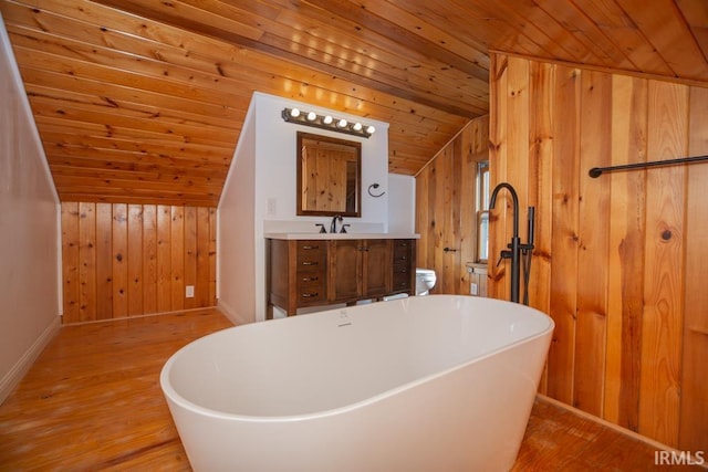 full bathroom with wooden walls, wood ceiling, wood finished floors, vanity, and a freestanding tub