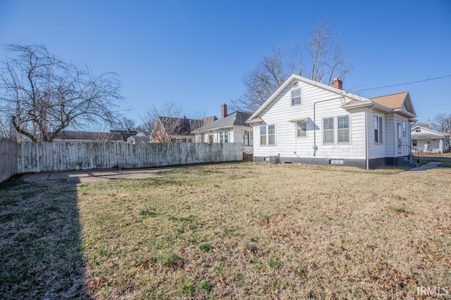 rear view of property with a chimney, fence, and a lawn