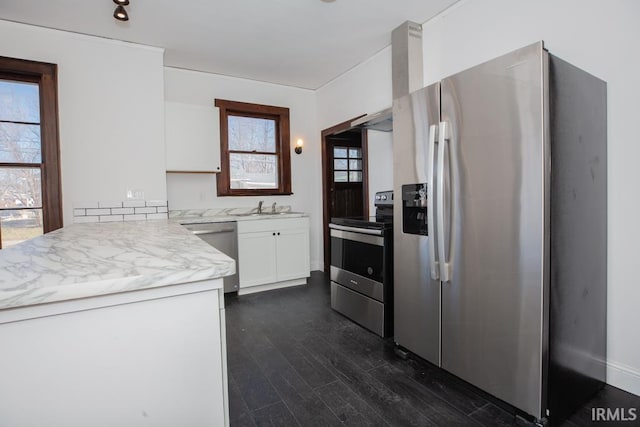 kitchen with dark wood finished floors, light countertops, appliances with stainless steel finishes, white cabinetry, and a sink