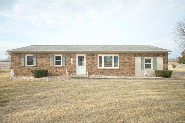 single story home with brick siding, a front yard, and a shingled roof