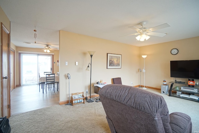 carpeted living area featuring a ceiling fan and baseboards