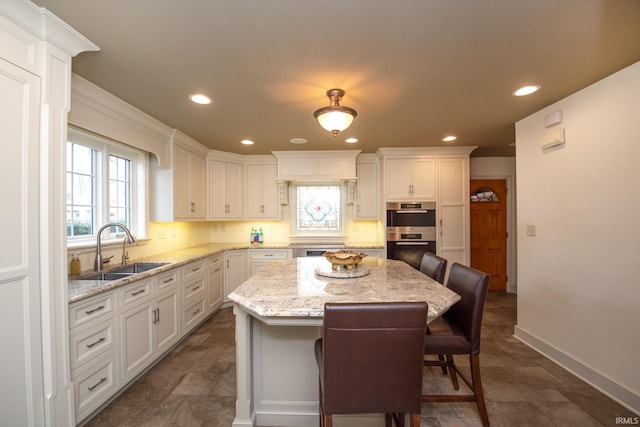 kitchen with double oven, a breakfast bar area, a sink, and decorative backsplash