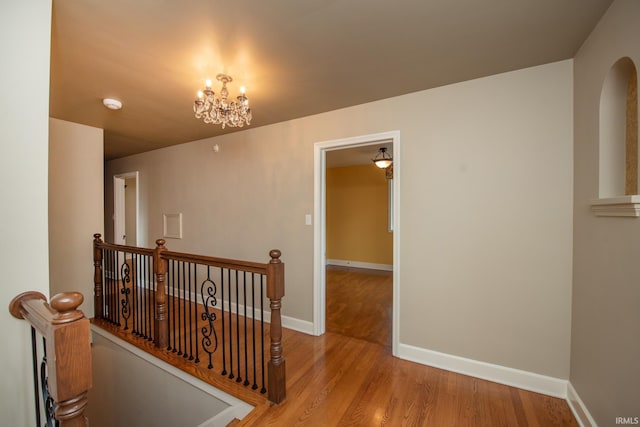 corridor featuring baseboards, an upstairs landing, and wood finished floors