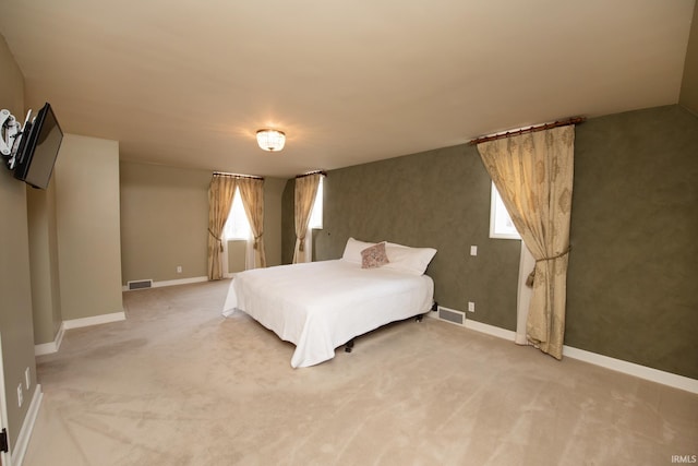 bedroom featuring light colored carpet, visible vents, and multiple windows