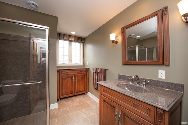 bathroom with a stall shower, vanity, baseboards, and tile patterned floors