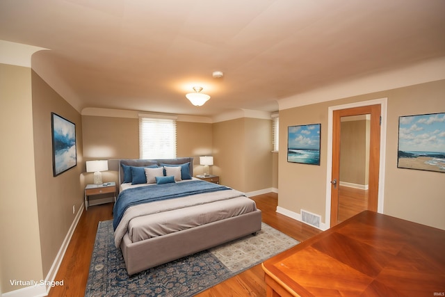 bedroom with baseboards, visible vents, and wood finished floors