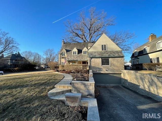 view of front of house featuring a garage, concrete driveway, and a chimney