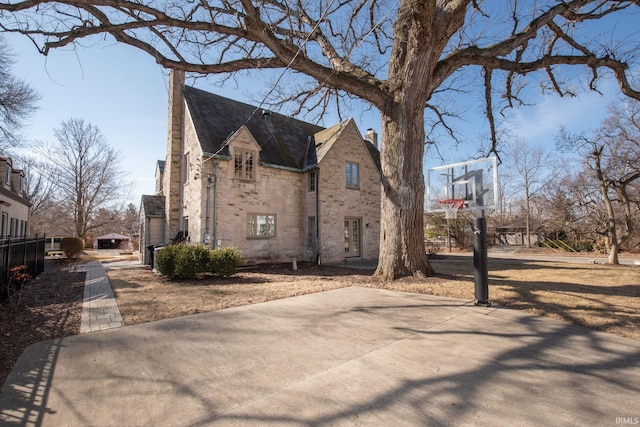 view of side of home with stone siding and fence