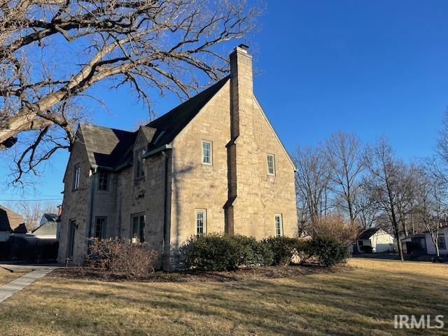 view of side of property featuring a lawn and a chimney