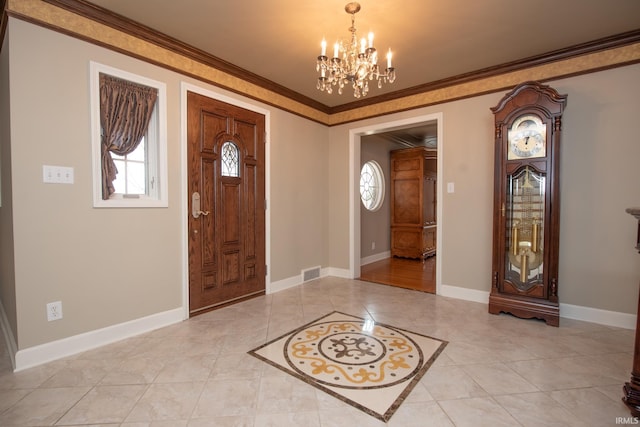 entryway with an inviting chandelier, baseboards, visible vents, and crown molding