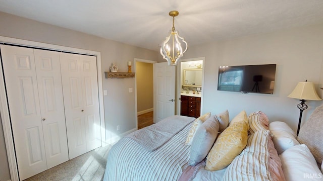 carpeted bedroom featuring baseboards, a closet, and a notable chandelier