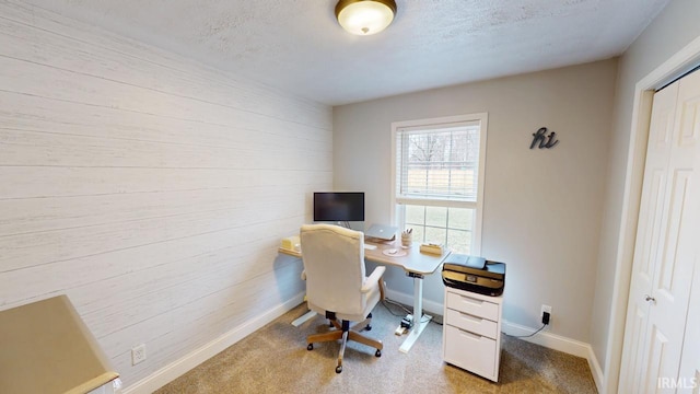 home office featuring carpet, wooden walls, baseboards, and a textured ceiling