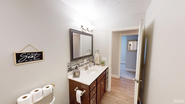 bathroom featuring tasteful backsplash, wood finished floors, vanity, and baseboards