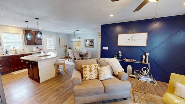 living room with light wood-style floors, recessed lighting, ceiling fan, and baseboards