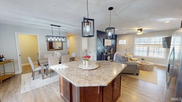 kitchen with decorative light fixtures, a kitchen island, freestanding refrigerator, and light wood-style floors