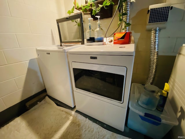 washroom featuring concrete block wall, laundry area, and washing machine and clothes dryer