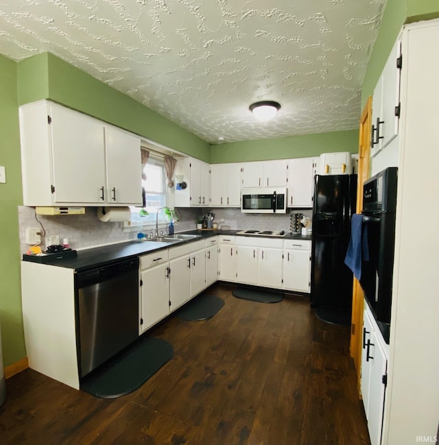 kitchen featuring a sink, backsplash, dark wood-style floors, black appliances, and dark countertops