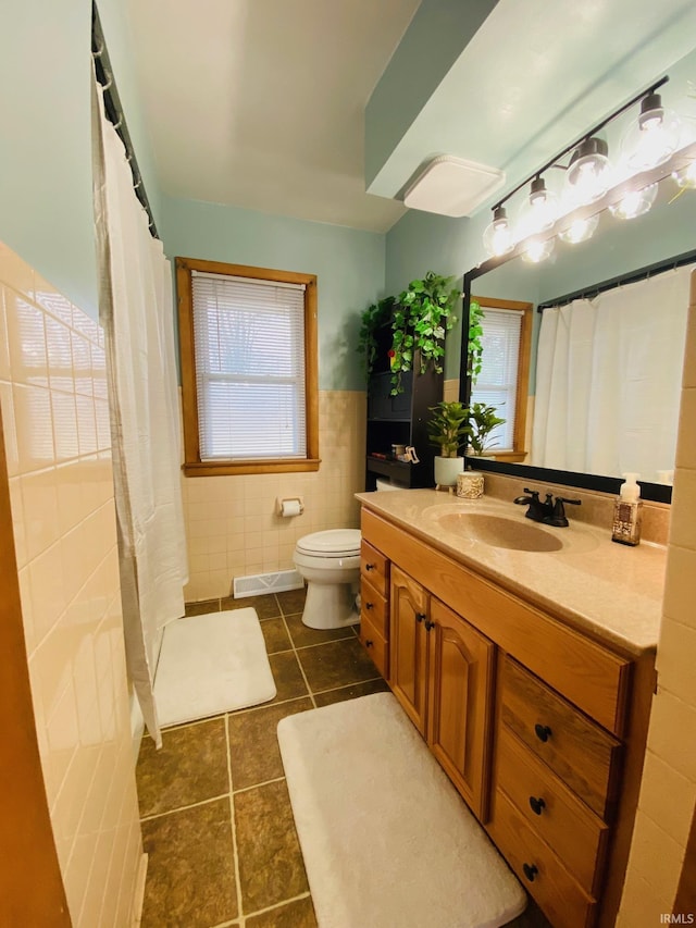 bathroom featuring visible vents, toilet, tile patterned flooring, vanity, and tile walls