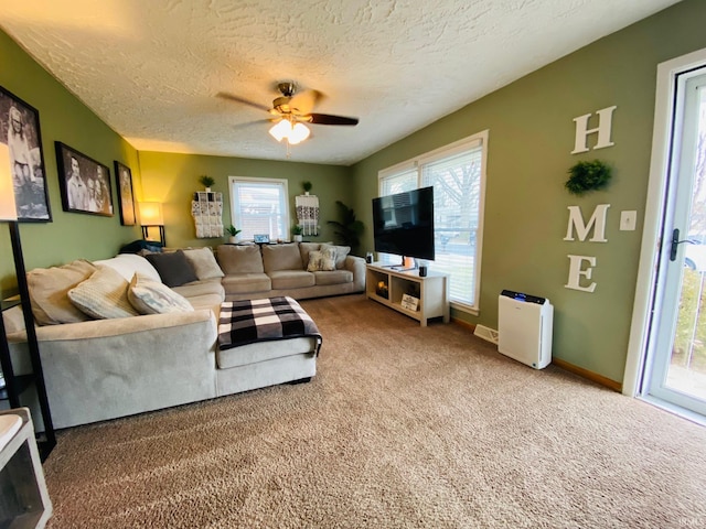 carpeted living area with a ceiling fan, a textured ceiling, and baseboards