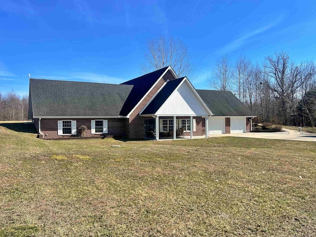 view of front of home with an attached garage, driveway, brick siding, and a front yard