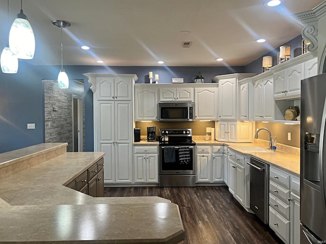 kitchen featuring dark wood finished floors, appliances with stainless steel finishes, white cabinetry, a sink, and recessed lighting