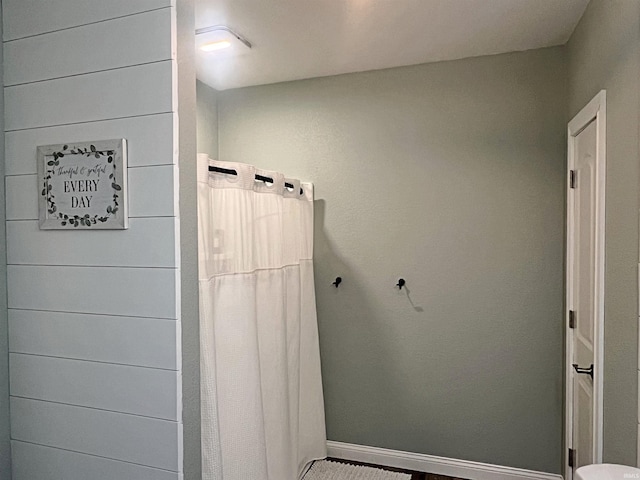 full bath featuring curtained shower and baseboards