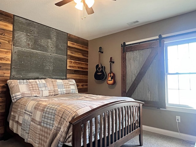 bedroom with carpet floors, a barn door, multiple windows, and visible vents