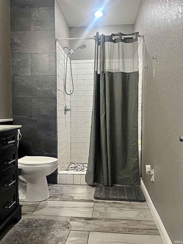 bathroom featuring a textured wall, toilet, vanity, a shower stall, and wood finish floors