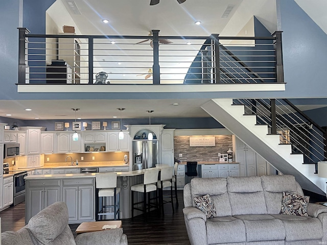 living area with stairs, dark wood finished floors, a towering ceiling, and recessed lighting