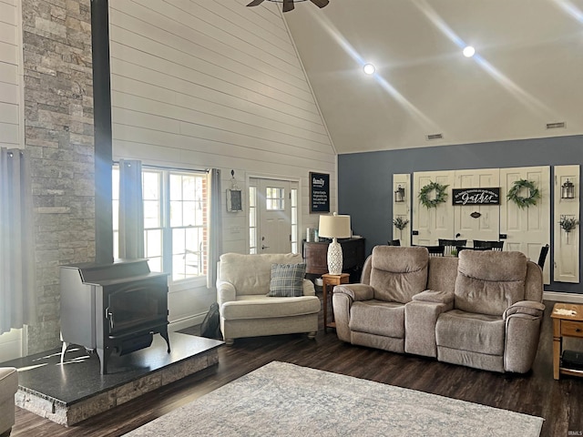 living room with visible vents, high vaulted ceiling, dark wood-type flooring, and a wood stove