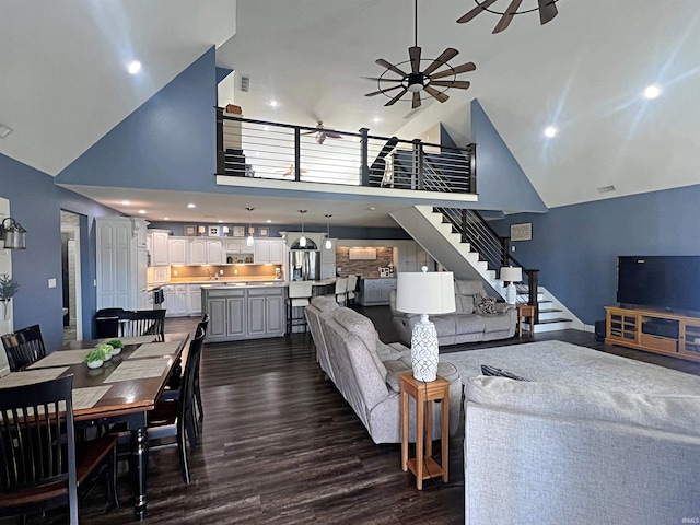 living area featuring high vaulted ceiling, recessed lighting, dark wood-style flooring, a ceiling fan, and stairs