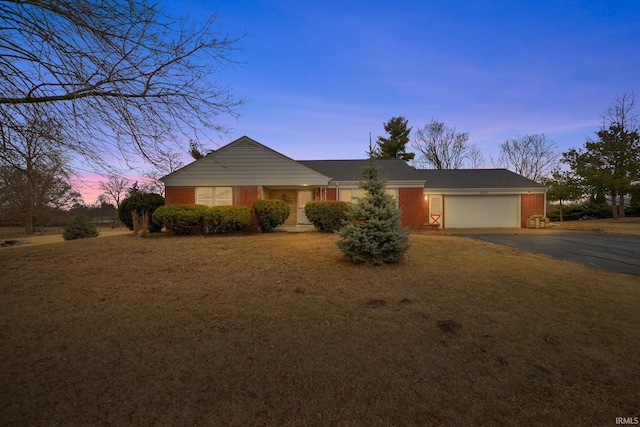 ranch-style home with a front yard, brick siding, driveway, and an attached garage