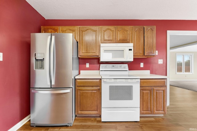 kitchen featuring light countertops, white appliances, light wood-type flooring, and baseboards