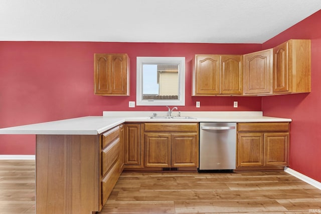 kitchen with dishwasher, a peninsula, a sink, and light wood-style flooring