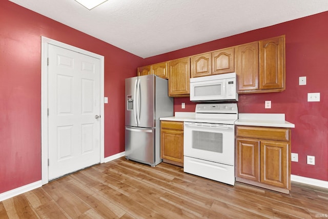 kitchen with white appliances, baseboards, light countertops, and light wood finished floors