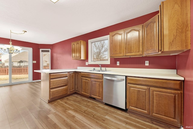 kitchen with light countertops, dishwasher, a peninsula, and a sink