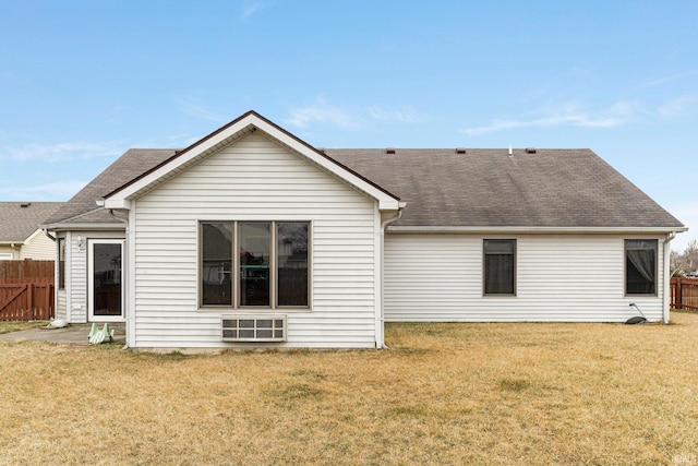 back of house featuring a shingled roof, a lawn, and fence