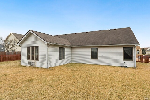 rear view of property with roof with shingles, fence, and a yard