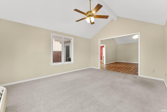 carpeted spare room with lofted ceiling with beams, a ceiling fan, and baseboards