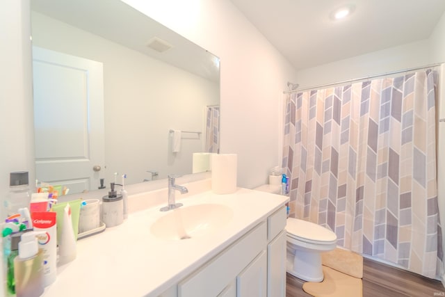 bathroom featuring toilet, wood finished floors, visible vents, vanity, and a shower with curtain