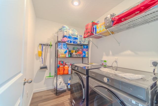 clothes washing area featuring laundry area, baseboards, washer and clothes dryer, and wood finished floors