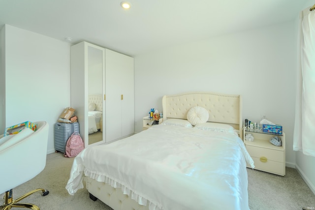 bedroom with light colored carpet and baseboards