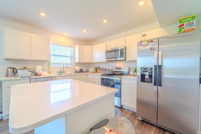 kitchen with recessed lighting, a sink, light countertops, appliances with stainless steel finishes, and light wood finished floors